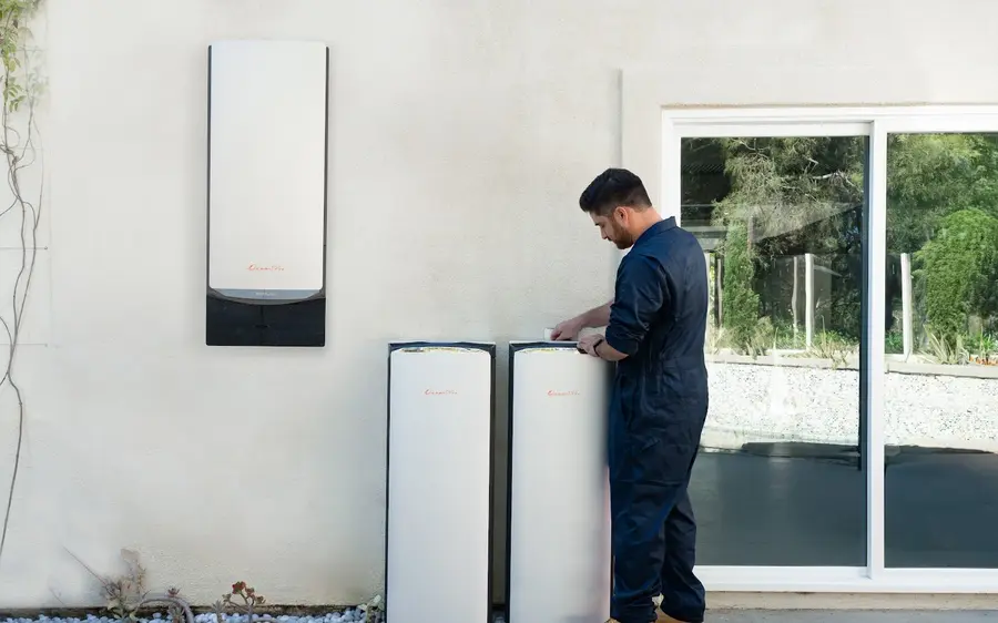 A home battery installation: a wall mounted inverter unit with floor standing battery modules beside it.